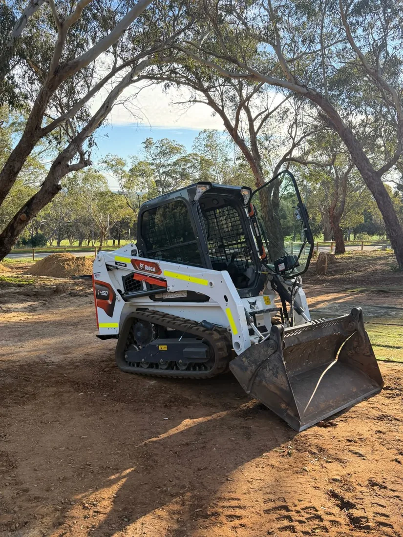 Bobcat T450 tracked loader with a four in one bucket held open, showing the split clamshell jaw