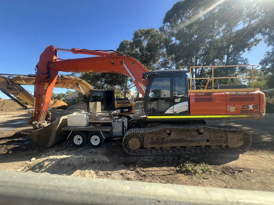 Tracked excavator standing on a Perth site beside a plant trailer