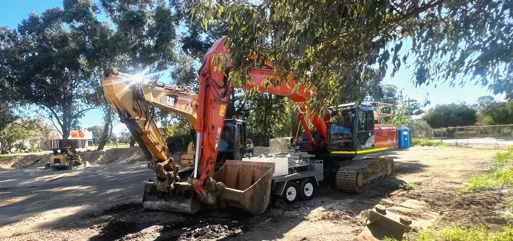 Perth earthworks job site with two tracked excavators behind a wet hire inclusions checklist