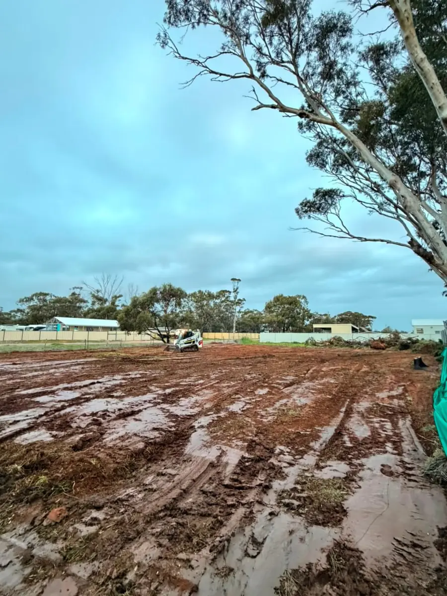 Wide view of a cleared acreage block worked back to bare earth after rain
