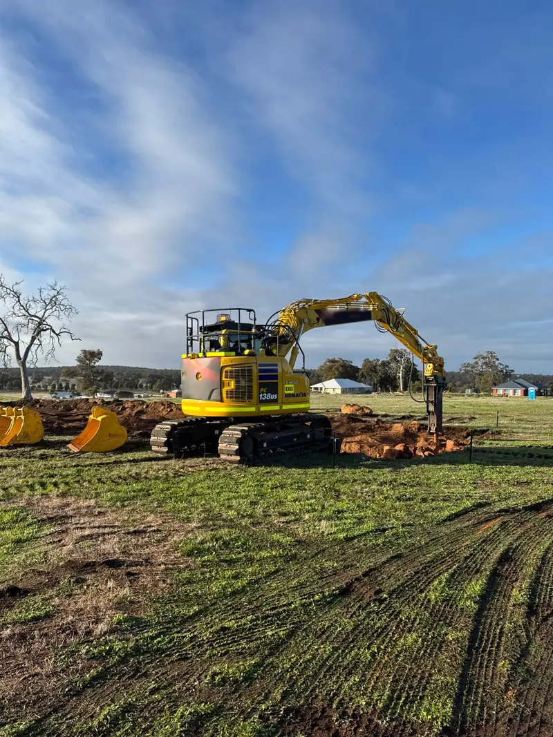13.8 tonne excavator fitted with a hydraulic rock breaker working broken rock on a cleared paddock