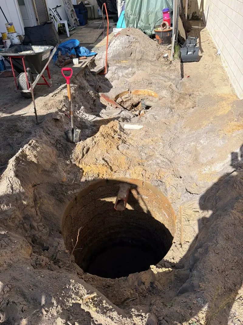 Excavation opened out to a deep circular hole with old pipework showing through the wall of the dig