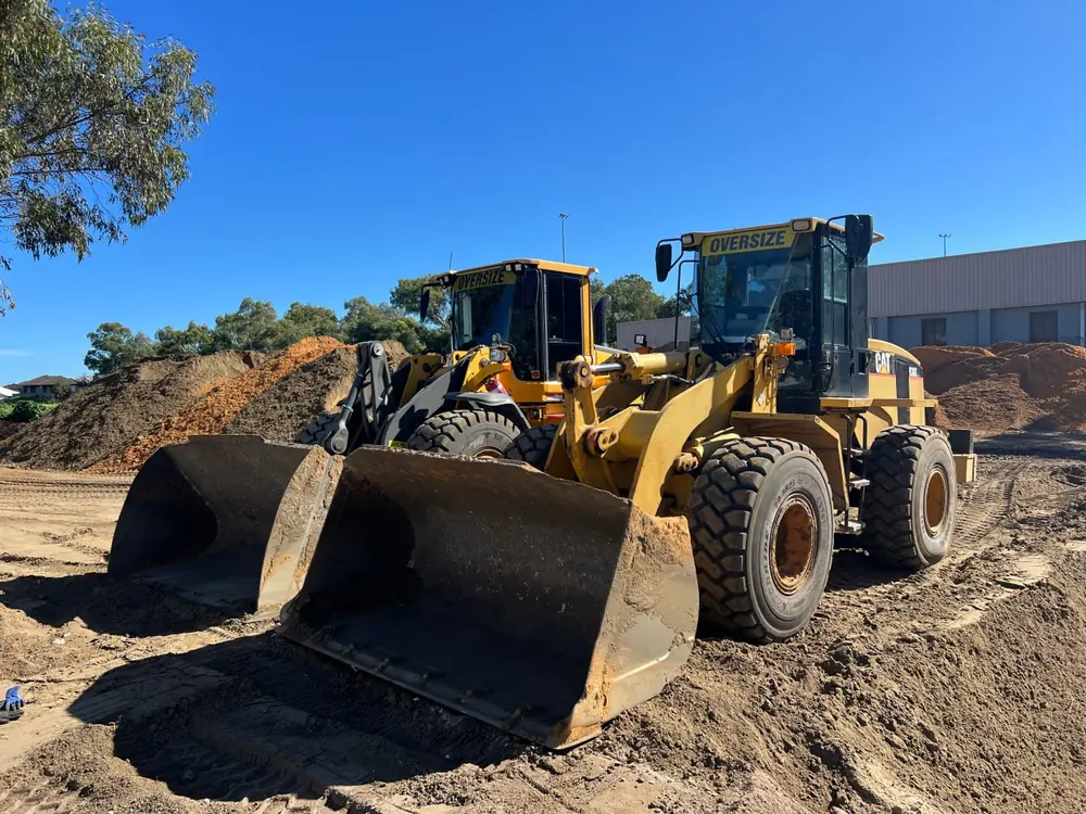 Two CAT wheel loaders parked with their buckets down in a Perth soil yard behind the dry hire inclusions checklist